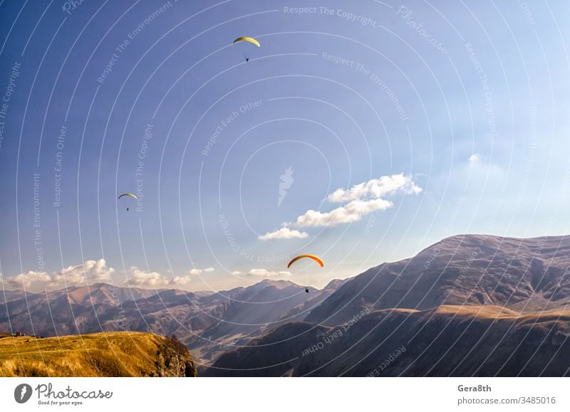 three paragliders in sky against the background of Caucasus mountains adrenalin clouds day europe extremal extreme extreme sport fly flying grass high
