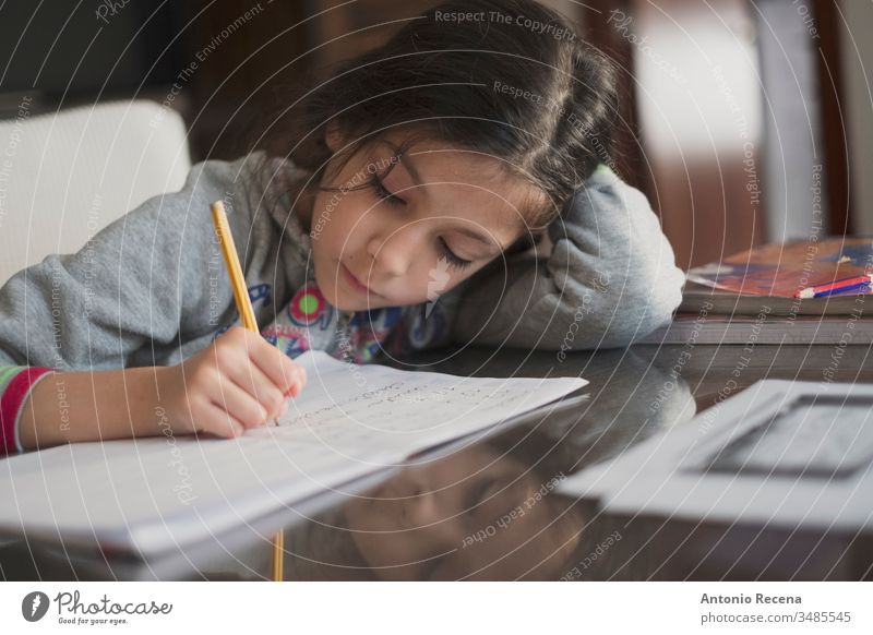 Seven years old girl doing homework at home education student writing 7s sitting people person kid pencil child childhood children candid focus in foreground