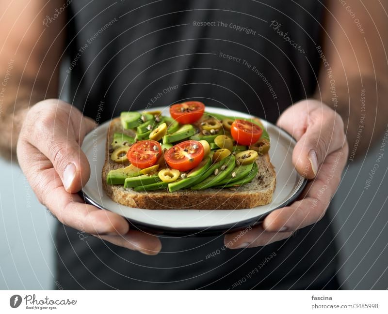 Vegan sandwich with avocado in male hands vegan toast veggie avocado toast plate plant-based ready-to-eat ideas healthy breakfast lunch snack concept copy space