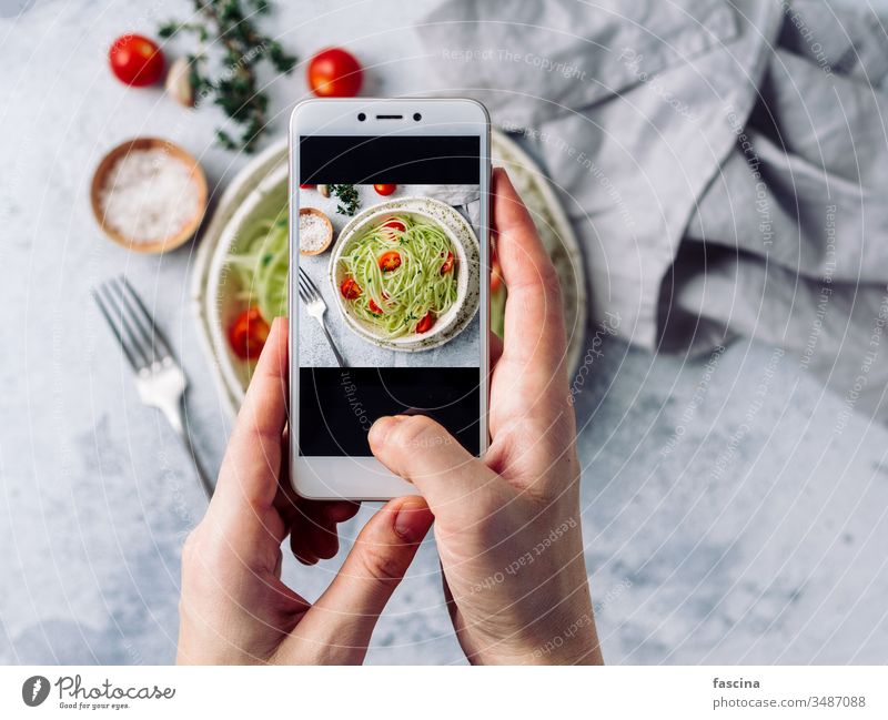 Zucchini noodles salad. Top view, copy space smartphone photography woman hand hold take social raw zucchini zoodles spaghetti diet food fresh healthy lunch