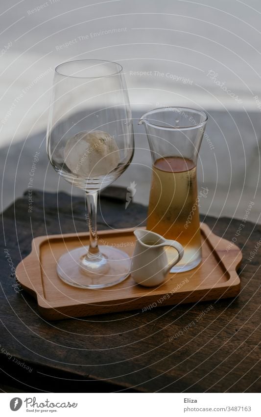 A tray with a glass and a carafe filled with a light liquid Wine glass Carafe Vine Iced tea Ice cube Summer out Tray serve Gastronomy Noble Alcoholic drinks