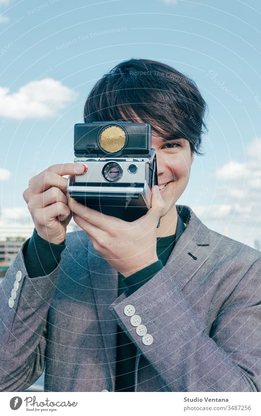 Young Mixed Race Photographer with Polaroid Camera on River Thames photographer smiling polaroid vintage business tourist young travel europe vacations