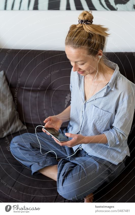 Woman at home relaxing on sofa couch using social media on phone for video chatting with her loved ones during corona virus pandemic. Stay at home, social distancing lifestyle.
