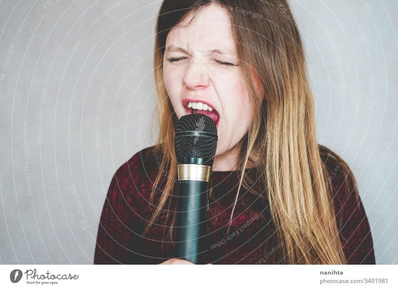 Young woman singing with a microphone loud techonology sound art artist concept leisure activity active blonde casual real people hobby trendy voice black