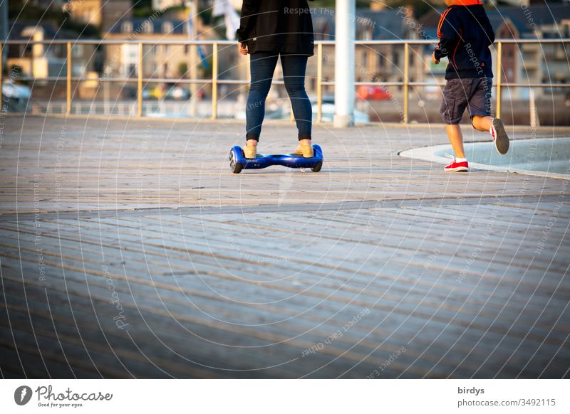 Adult rides on a Hoverboard, child runs, runs alongside Movement Electric locomotion Child Adults Youth (Young adults) Walking Driving Running Human being Legs