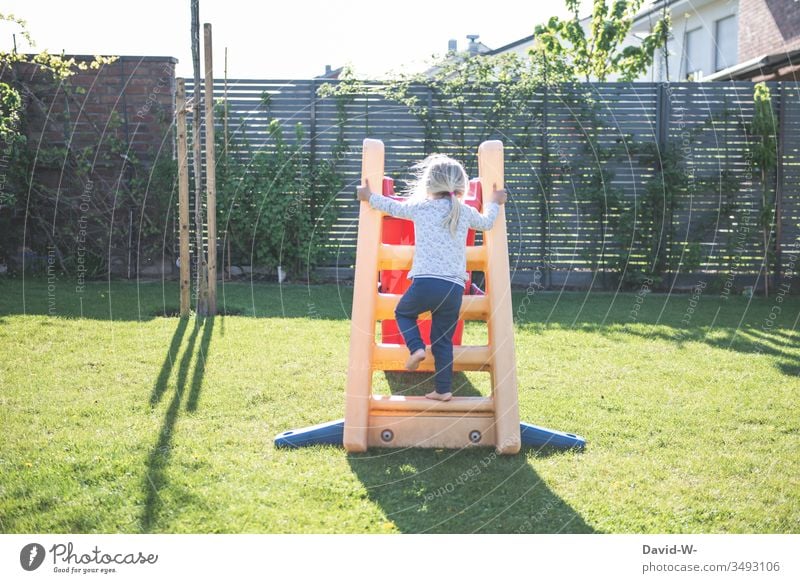 Child climbs up the slide in the garden Playing Garden Slide Skid at home Girl fun Joy Happiness Joie de vivre (Vitality)
