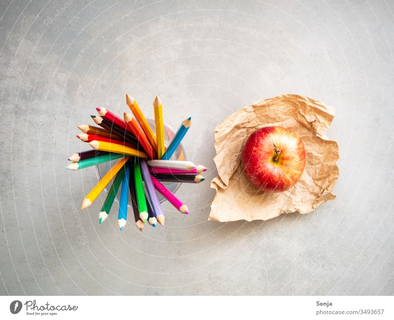 Draufsicht von Farbstiften und einem roten Apfel auf einem Backpapier, Bildung, Kunst, grauer Schultisch farbstift apfel Rotate bildung Schule kunst kreativ