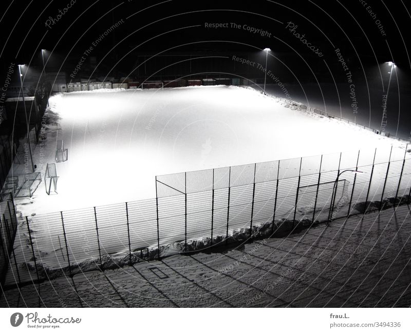 The snow-covered football field was ghostly and deserted, illuminated by pale lantern light. Foot ball Football pitch gates Winter Snow Evening lanterns Light