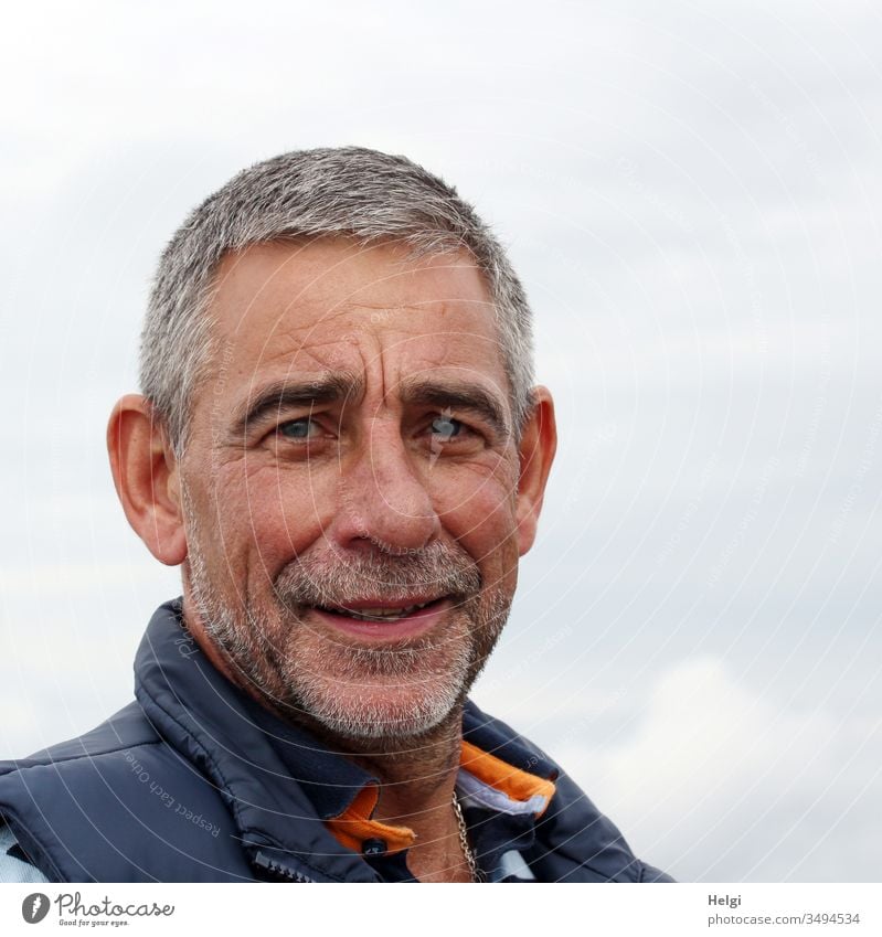 Portrait of a senior citizen with short grey hair and three-day beard in front of a blue-grey sky Human being Man Senior citizen portrait Gray-haired