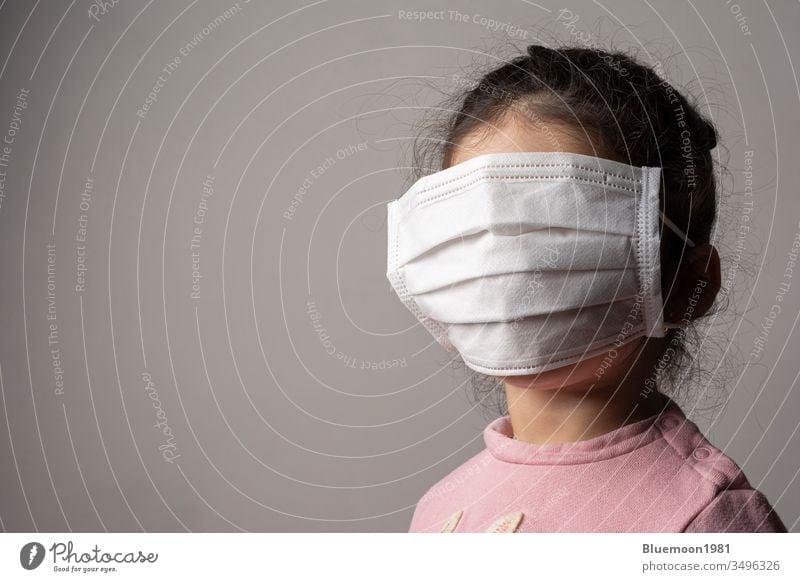 Covered face of a little girl with protection hospital mask wearing child concept virus corona medical pandemic portrait children safe alert care pollution big