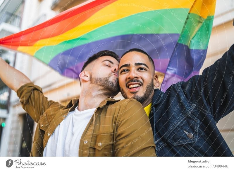 Gay couple embracing and showing their love with rainbow flag. lgbt homosexual freedom gay two partners proud closeness outside diversity support celebrate