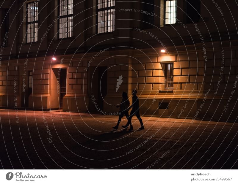 A couple is walking through Berlin at night adult adults architecture building exterior city dark darkness europe friends germany historic history illuminated