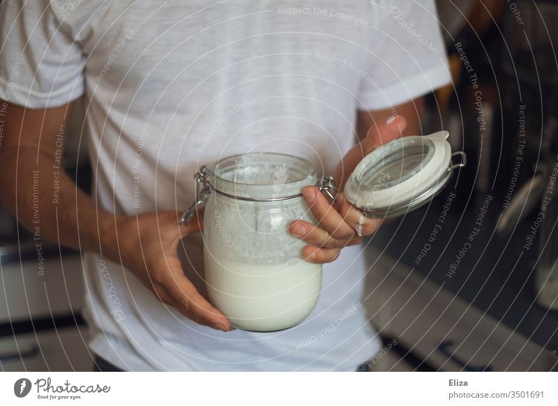A man holds a jar of homemade kefir in his hand Proteins Self-made Milk products albumen Nutrition Preserving jar White Man stop Delicious Kitchen salubriously