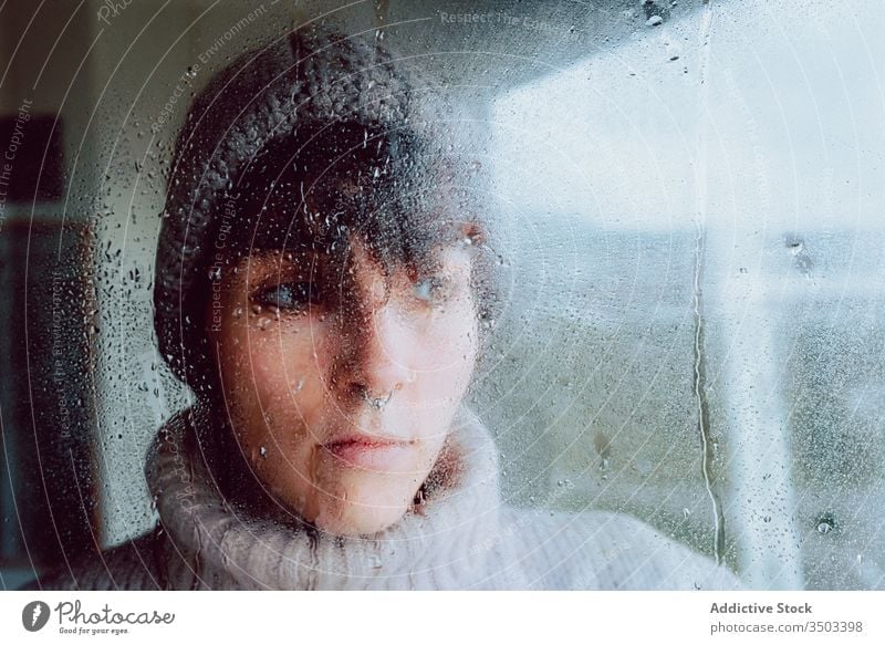 Melancholic young woman looking through window sad depression isolation coronavirus home desperate lonely unhappy female wet rain melancholy solitude stress