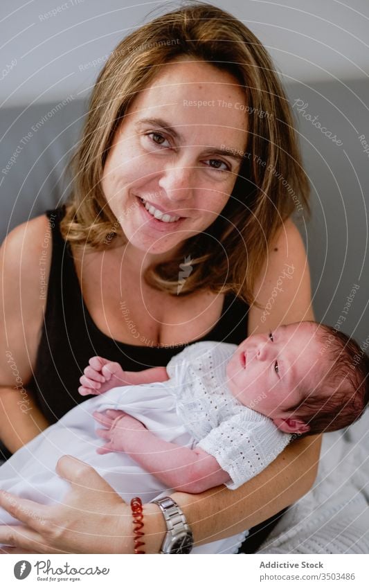 Happy mother with newborn baby child happy woman care together love smile kid parent adorable childhood innocent infant sofa motherhood little cute comfort