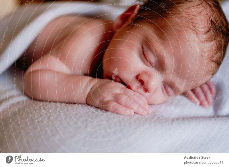 Sweet newborn sleeping in soft bed at home relax baby kid infant calm innocent rest little peaceful child cute face head silent comfort nap hand harmony