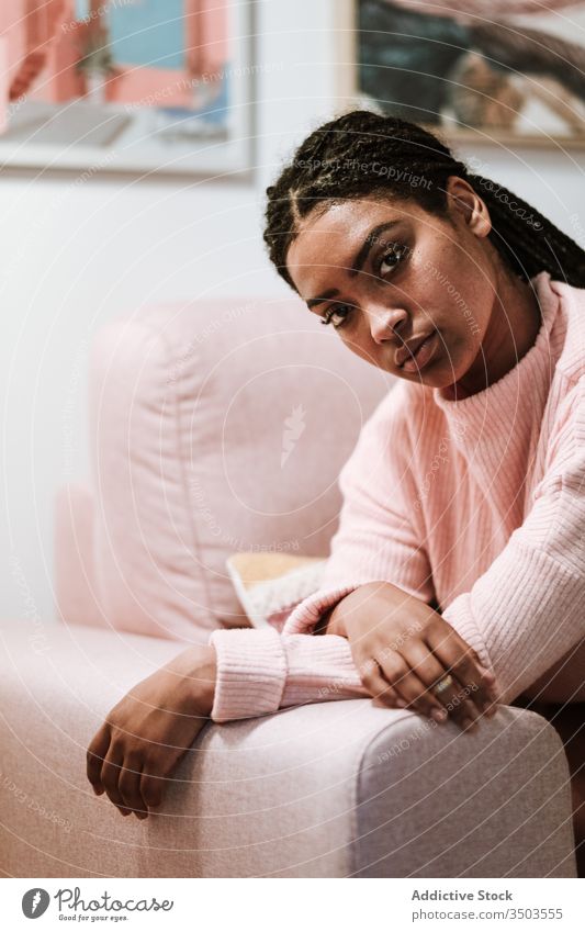 Bored young woman sitting on sofa home thoughtful bored casual rest pensive african american black ethnic couch relax lazy calm sad cozy peaceful think serious