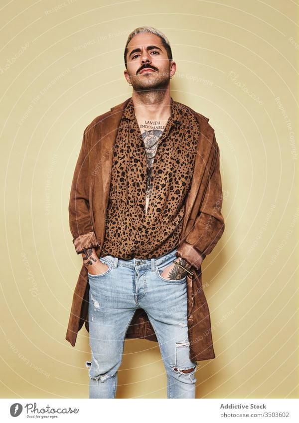 Trendy ethnic guy in stylish outfit standing in studio man trendy style fashion leopard coat model jeans beard male cloth modern cool confident handsome