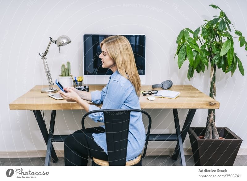 Blonde Caucasian woman works from her home office browsing computer typing desk communication businesswoman tablet indoor adult laptop desktop design lifestyle