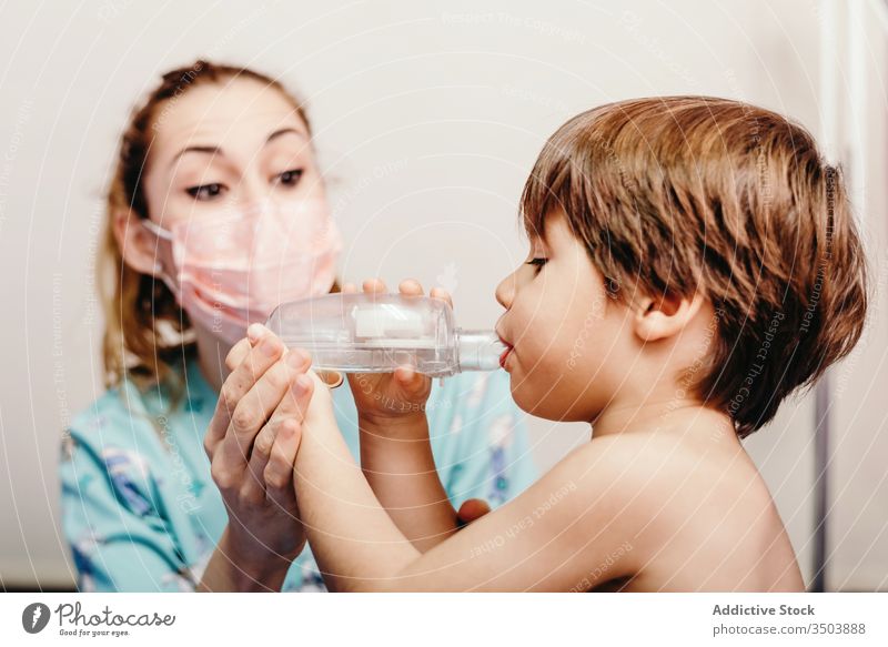 Little kid using inhaler in clinic during check up child respiration sick treat respiratory medicine medical doctor mask little woman hospital health care
