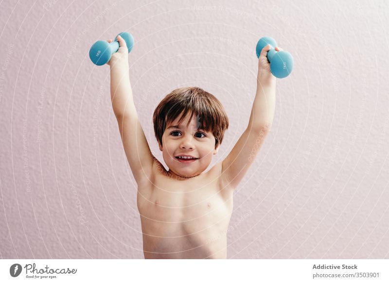 Cheerful little boy with dumbbells kid healthy happy active smile cheerful energy positive child exercise lifestyle joy training childhood glad health care