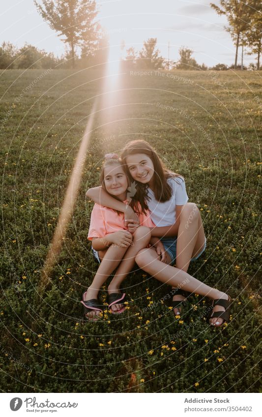 Happy kids hugging on green meadow sister nature together happy sit grass summer girl countryside cheerful teen teenage sibling friend rest embrace smile