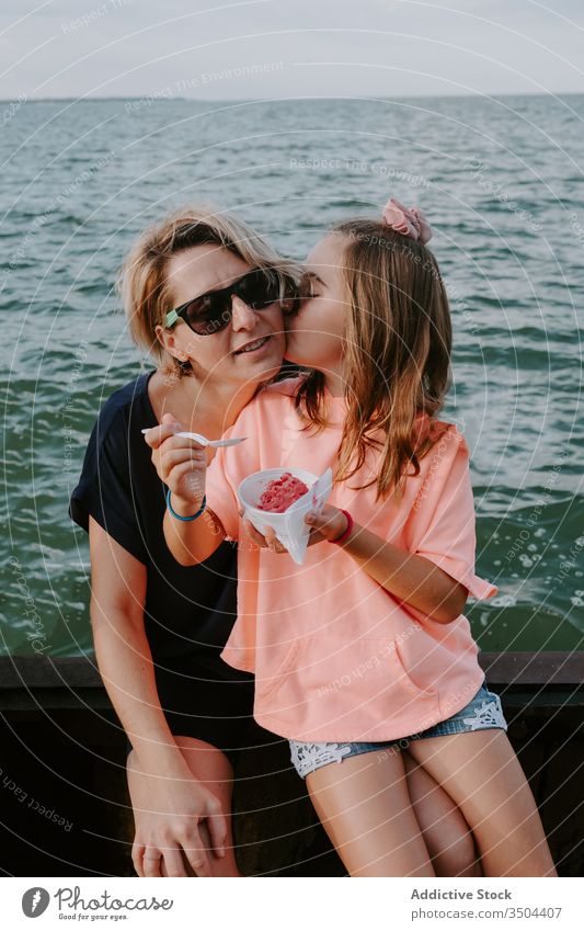 Woman with daughter resting near sea mother together kiss eat berry summer woman child girl kid fence bowl happy fresh parent love lifestyle relax vacation