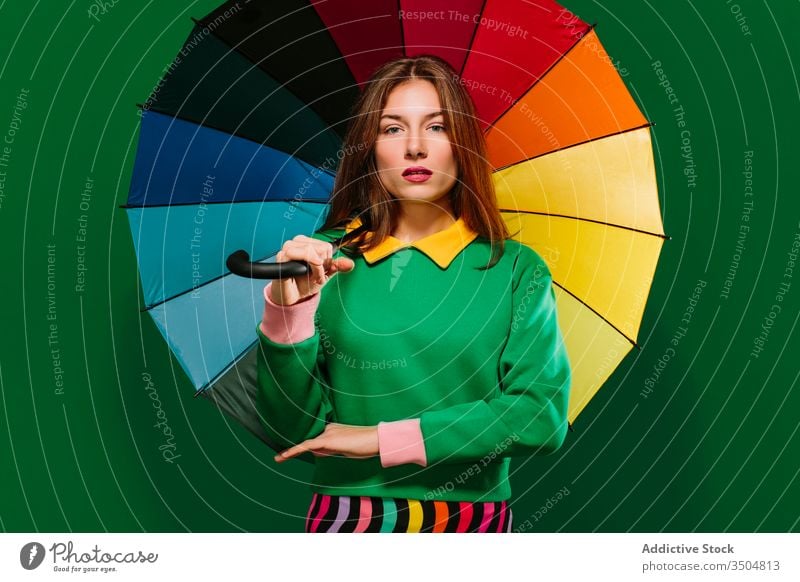 Young woman with colorful umbrella in studio style bright vivid young multicolored fashion female model unemotional emotionless urban serious confident