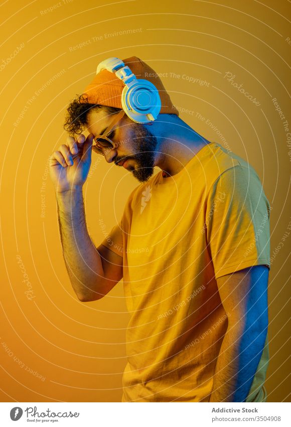 Bearded man with modern headphones urban style outfit music color bright male contemporary white yellow accessory hat sunglasses sound melody tune vivid vibrant