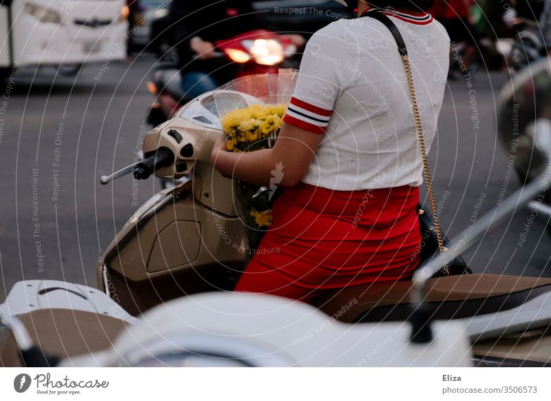 An elegantly dressed woman on a scooter in traffic with a bouquet of yellow flowers in her arms Woman urban Bouquet Transport Red Elegant City Modern Street