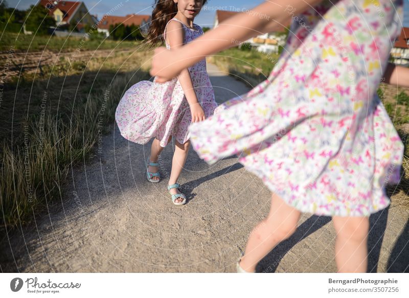 Two sisters play games Exterior shot Nature Day Sun Dress girl buzzer playtime