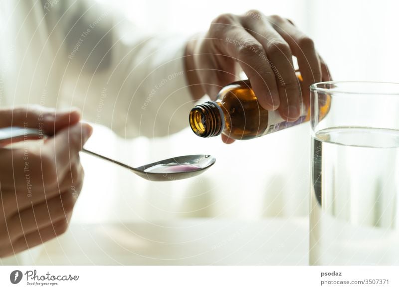 Woman hand pouring medication or cough syrup from bottle to spoon. healthcare concept adult alcohol baby background beverage child cold cup cure disease doctor