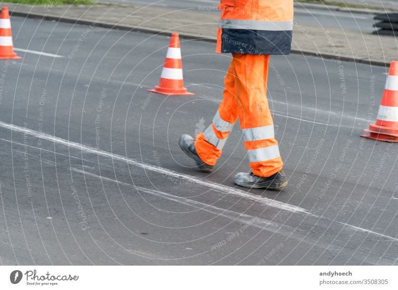 Road worker walks on the street with cones in the background asphalt asphalting attention barrier construction copy space danger equipment fix fixing highway