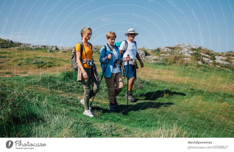 Family practicing trekking together outdoors family hiking mountain field walking nature senior journey tourism people hikers backpack women girl daughter