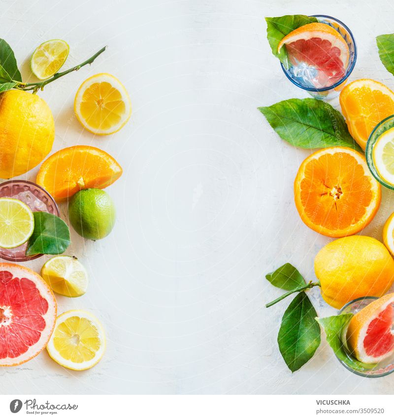 Frame of various citrus fruits with green leaves on white table, top view. Healthy lifestyle. Ingredients. Vitamin. Halves and slices. Layout frame healthy