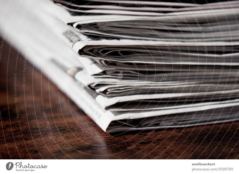 pile of newspapers or papers table desk print media heap stack information press journalism business publication current events recycling recycle reading