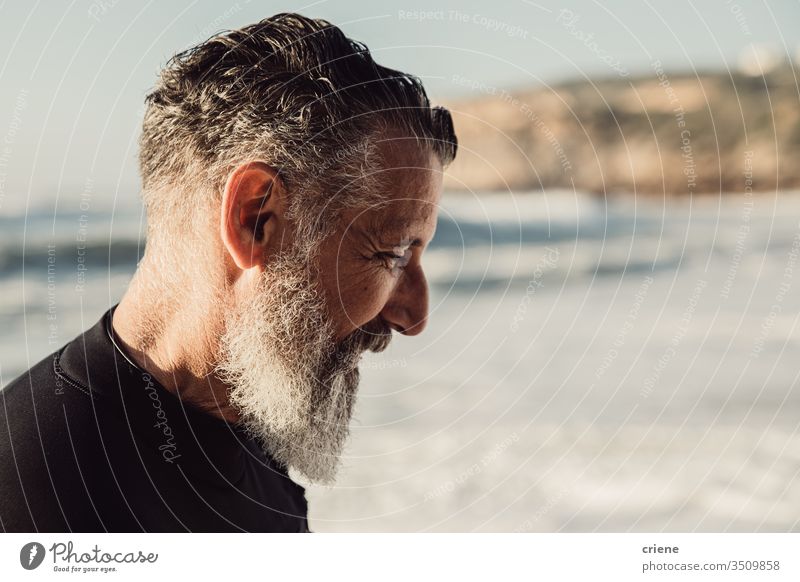 Senior man with long beard smiling at beach senior men vacation surfing adult smile grey hair lifestyle joy sport hobby portrait ocean waves adventure outdoor