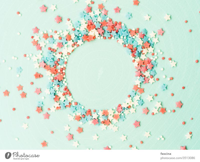 Sprinkles in round spahe on blue, copy space sprinkles top view isolated pastel stars dots circle shape flat lay center design background above text bakery cake