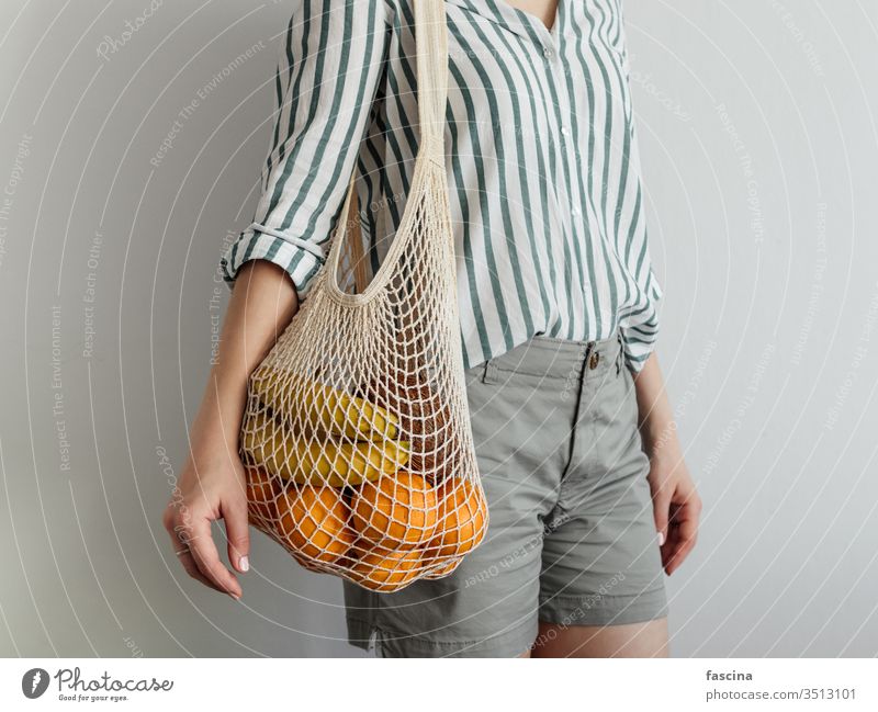 woman standing with mesh bag on shoulder zero waste fruits female shopping casual style modern concept fabric string grocery reusable food market cafe stylish