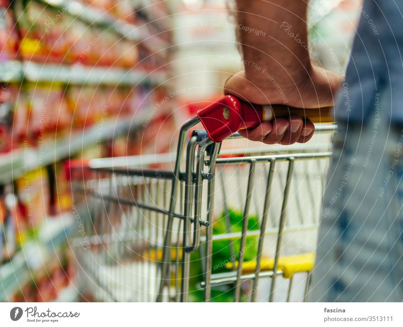 shopping trolley in supermarket aisle, copy space grocery cart man hands latin caucasian hold food store retail shelf customer hypermarket consumer consumerism