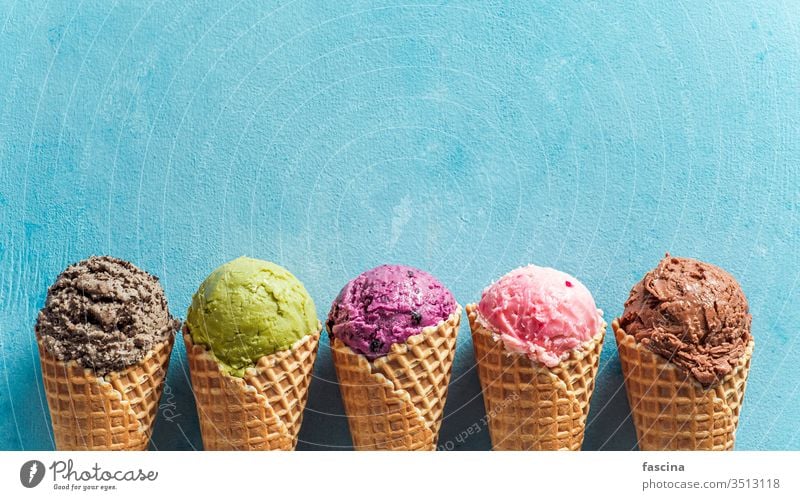 ice cream scoops in cones with copy space on blue gelato sundae banner background summer above ball biscuits blueberry chocolate cold colorful concept cookies