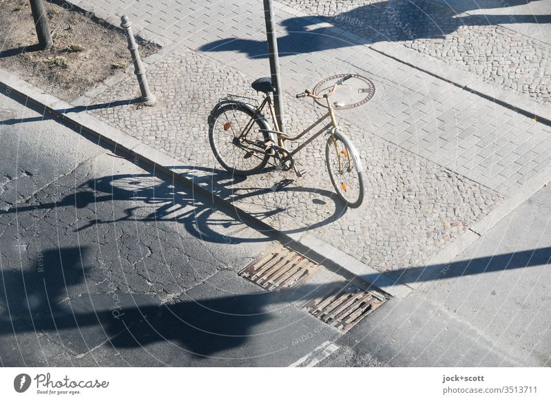with long shadows centrally located Bicycle Asphalt Street Traffic infrastructure Associated stake Sidewalk Cobblestones cracks Curbside Abstract Gully