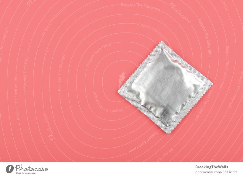 Close up one condom pack over pink background Condom silver foil wrap closeup pastel elevated high angle top view directly above copy space protection medicine