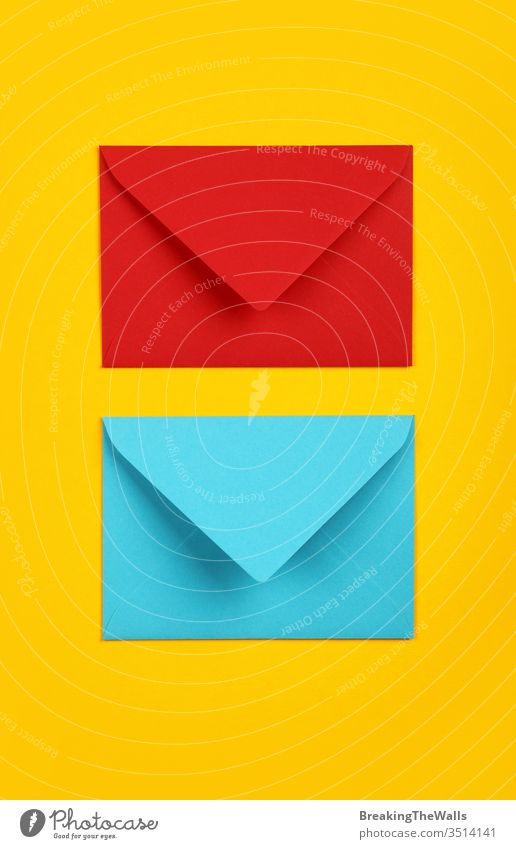 Two closed blue and red paper envelopes on yellow Envelope two pastel vivid background closeup color colorful multicolor post mail message communication blank