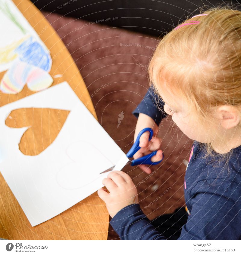 Girl cuts out hearts from sheet of paper with scissors Handicraft Claw Paper colored pencils paint Creativity Craft afternoon Heart cuddle Colour photo