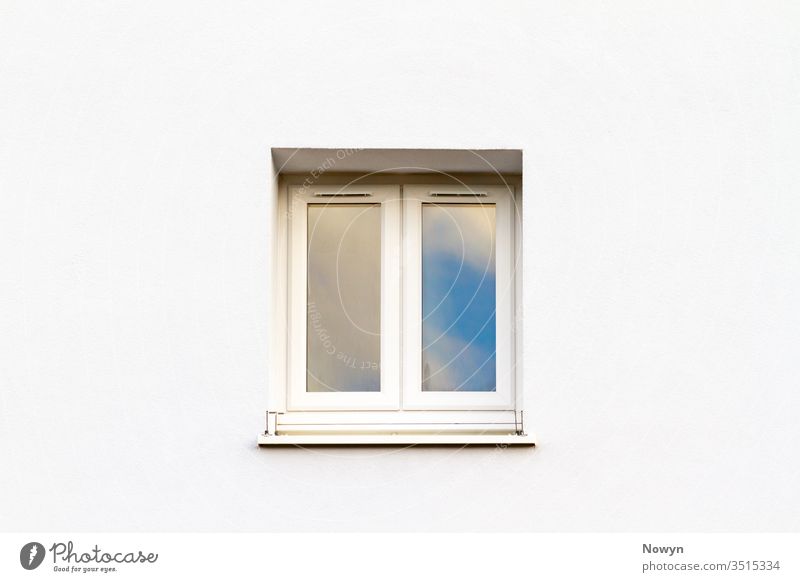 Closed white modern window on a white house wall reflecting blue sky building exterior clean clear close up closeup copy space copyspace detail double frame