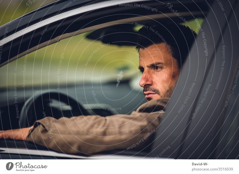 Man sits in car and looks seriously out the window Earnest view outside Rear view mirror Mirror look back Road traffic Car Window Open Exasperated Sour Evil