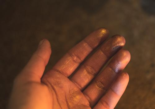 A palm with gold glittering colour on it by hand Colour golden sparkle Glittering painting valuable Gold dust Painted Close-up Fingers conceit candlelight