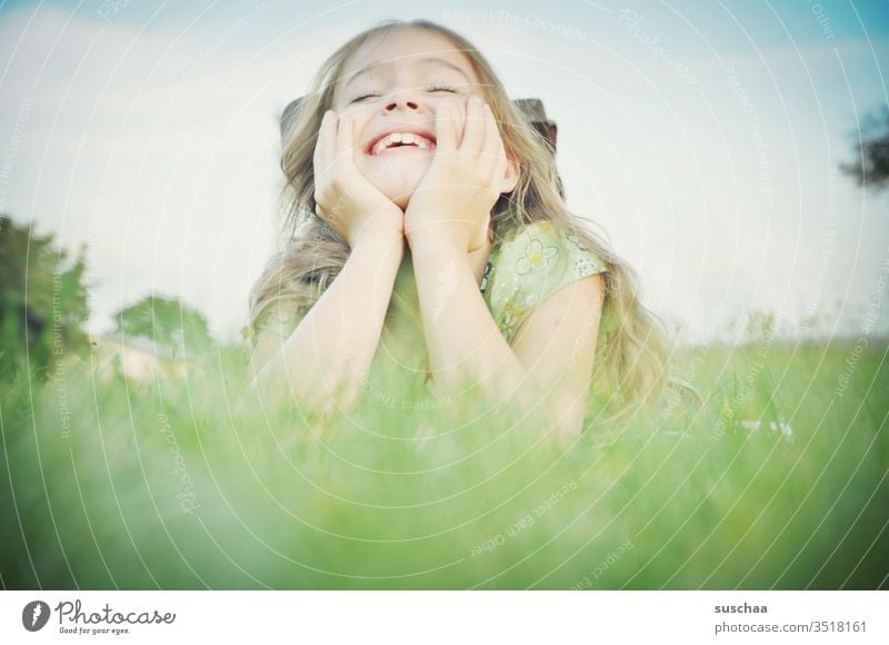 girl lies on propped up arms in the grass and laughs Child Infancy Joy Laughter Joie de vivre (Vitality) fun Ease Face hands Grass Lie smile luck Happiness