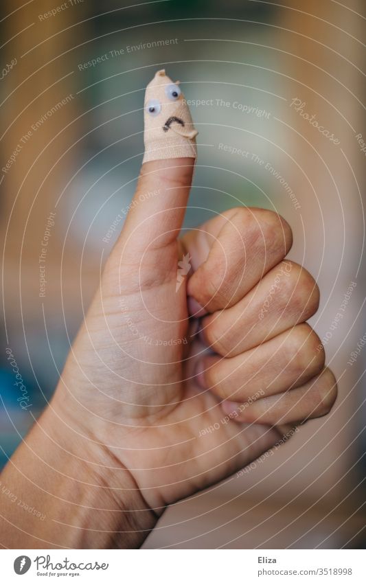 A thumb that was patched with a band-aid after an injury with a sad face on  it - a Royalty Free Stock Photo from Photocase